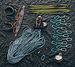 Closeup shot of a variety of carabiner hooks, rope, and other safety equipment used for rock or mountain climbing against a dark background. Needed for people passionate about extreme sport