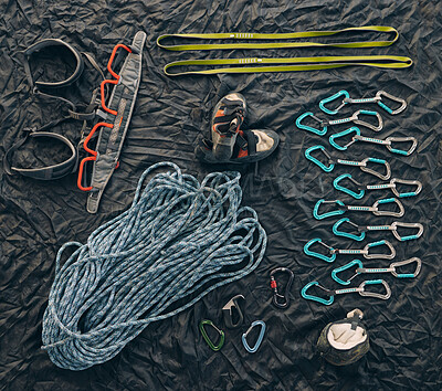 Closeup shot of a variety of carabiner hooks, rope, and other safety equipment used for rock or mountain climbing against a dark background. Needed for people passionate about extreme sport