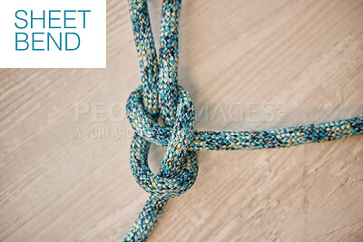 Above shot of hiking rope tied in a knot against a wooden background in studio. Sheet bend knot, A knot for every situation. Strong rope to secure safety while mountain climbing or extreme sports