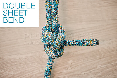 Above shot of hiking rope tied in a knot against a wooden background in studio. Double sheet bend knot for every situation. Strong rope to secure safety while mountain climbing or extreme sports