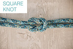 Above shot of hiking rope tied in a knot against a wooden background in studio. Square knot.  A knot for every situation. Strong rope to secure safety while mountain climbing or doing extreme sports