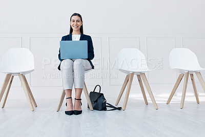 Young caucasian woman using a laptop while sitting and waiting in line on a chair for interview. Candidate browsing online to prepare for job vacancy. Potential candidate shortlisted for opportunity