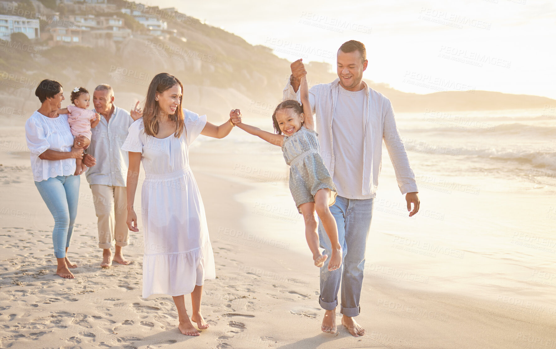 Buy stock photo Cute little girl swinging while holding hands with her parents. Young mom and day walking hand in hand with their daughter and lifting her while walking on the beach. Family fun in the summer sun