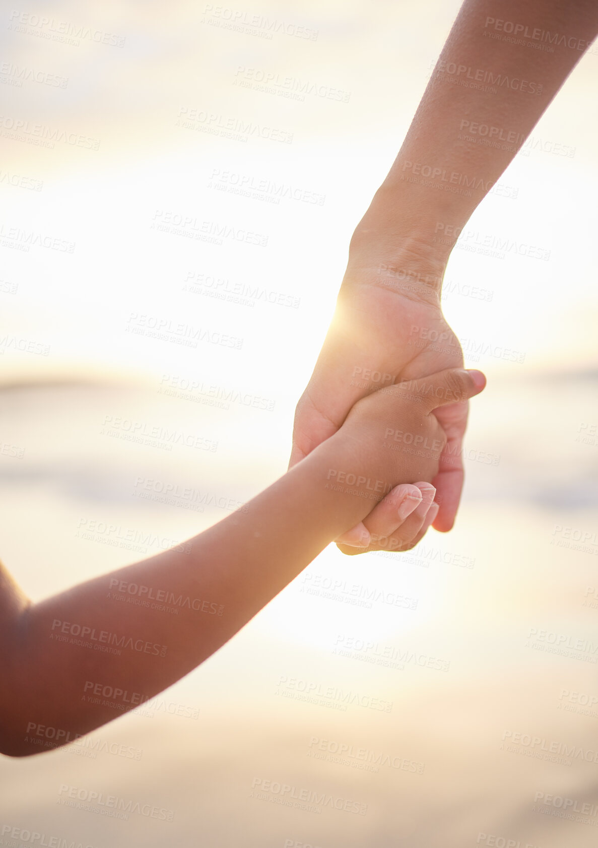 Buy stock photo Closeup of unknown mixed race mother holding her little son or daughter's hand while bonding together on the beach at sunset. Hispanic child showing trust in single mother. Loving and caring parent