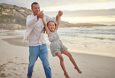 Buy stock photo Cute little girl swinging while holding hands with her father. Young dad walking hand in hand with his daughter and lifting her while walking on the beach. Family fun in the summer at sunset