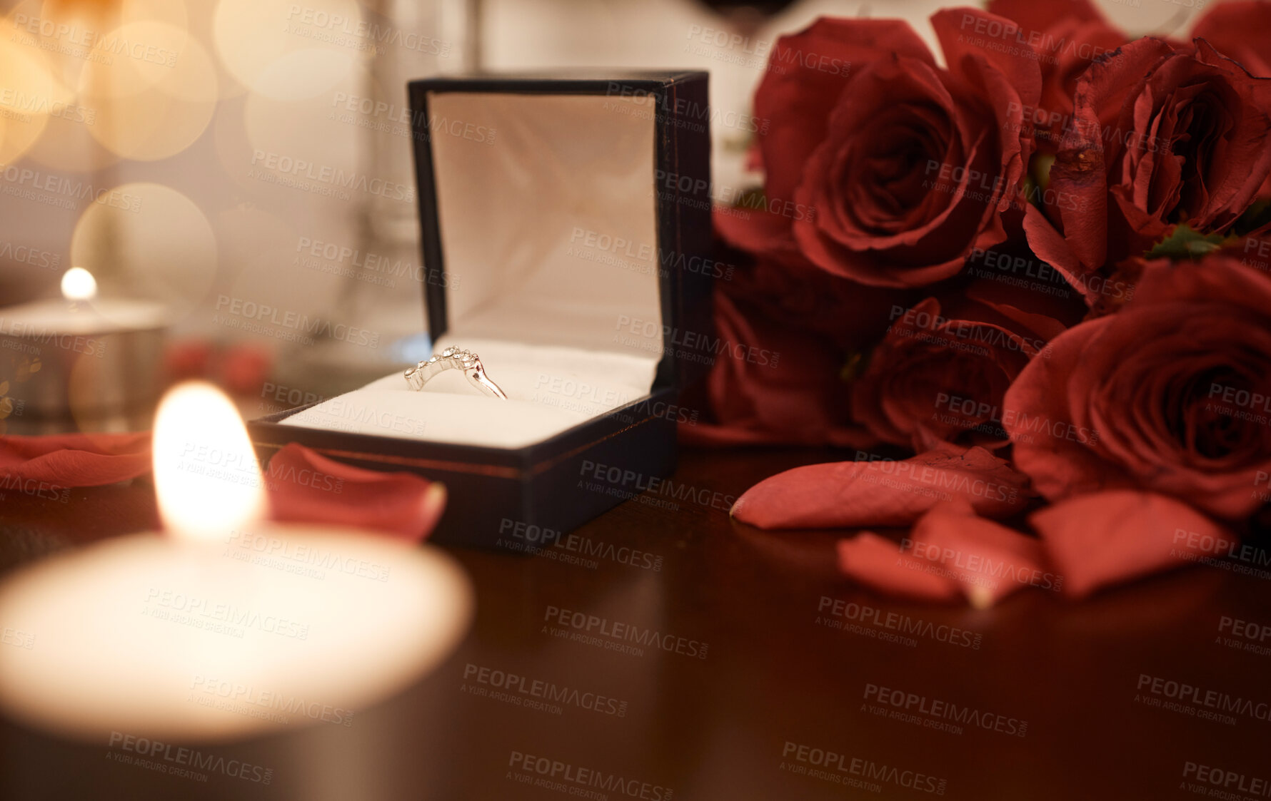 Buy stock photo Closeup of romantic engagement ring box, fresh red roses and candles in an empty room at night. Getting ready and prepared for  surprise proposal. Loving couple popping the question with sweet gesture