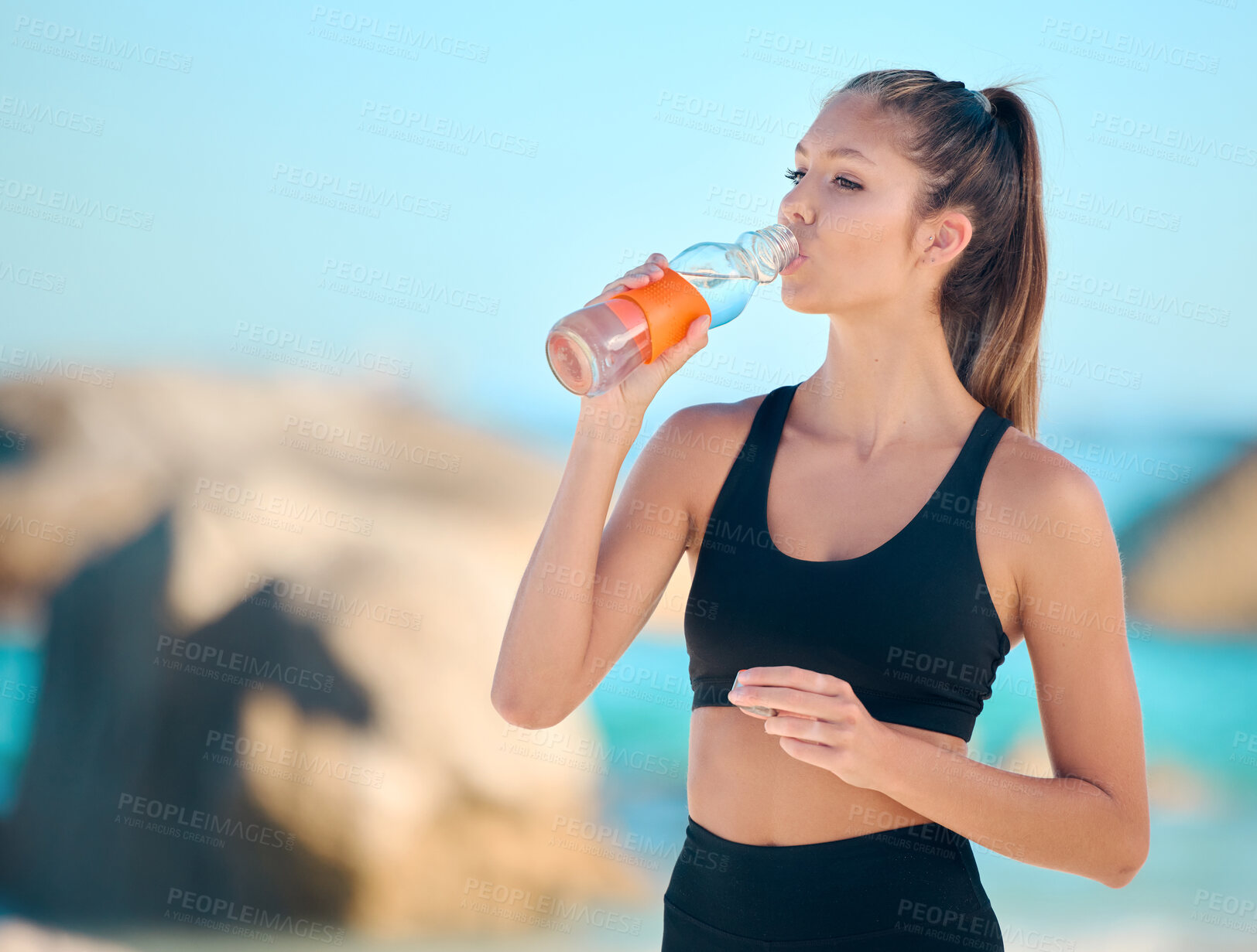 Buy stock photo Athlete, woman and drinking water at the beach for fitness, exercise or training at the sea. Girl, person and drink from bottle in outdoor workout, yoga and calm break or rest in summer exercising