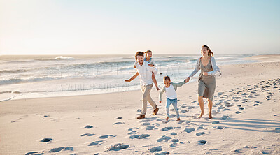 Buy stock photo Happy family walking on the beach together. Young caucasian family relaxing together on the beach. Parents bonding with their children by the ocean. Mother and father walking with their children
