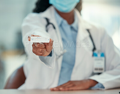 African american doctor holding a negative covid test. Hand of a medical professional holding a corona virus test. Doctor wearing a mask to protect from the covid disease.