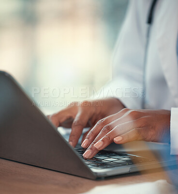 Doctor working on their laptop in the hospital. hands of a doctor typing on their computer sitting at the desk. Closeup on hands of medical professional working online on a wireless laptop