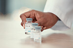 Closeup of doctor putting bottles of covid vaccine on a table. Hands of a doctor holding corona virus antidote. Healthcare professional putting medicine on a table. Hands of a gp holding covid cure