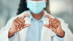 Doctor holding bottles of the covid antidote. African American doctor holding vials of the corona virus cure. Saving the world one bottle at a time. Healthcare worker holding bottles of medicine