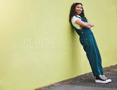 Fullbody beautiful mixed race fashion woman smiling with her arms crossed against a lime green wall background in the city. Young happy hispanic woman looking stylish, trendy. Carefree and fashionable