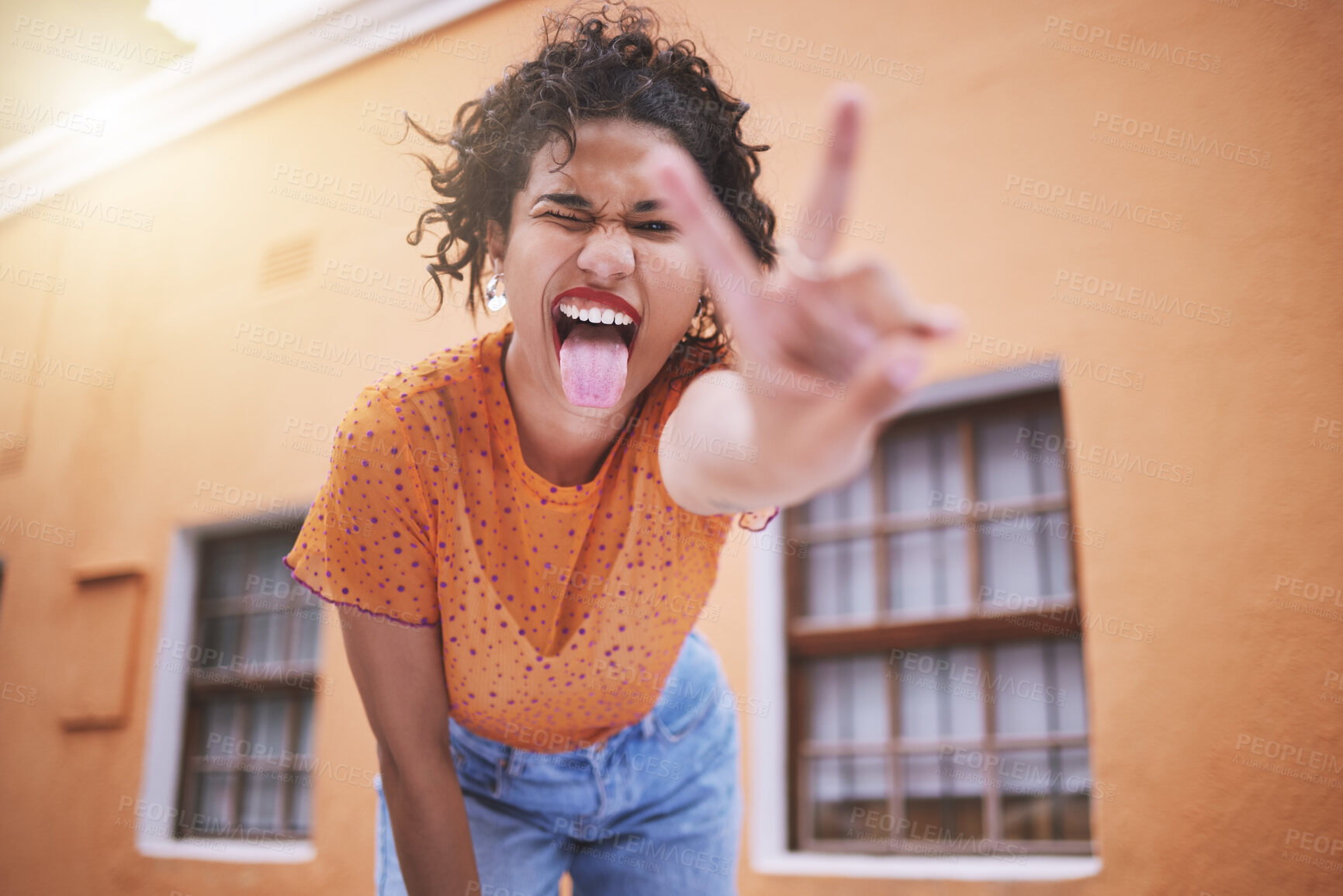 Buy stock photo Closeup beautiful mixed race fashion woman pouting and gesturing peace against an orange wall background in the city. Young happy hispanic woman looking stylish and trendy. Carefree and fashionable