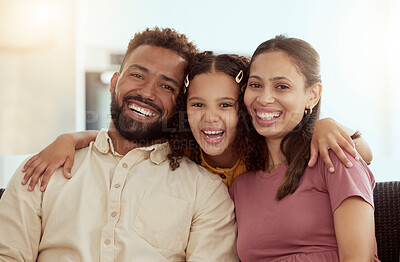 Portrait of mixed race parents enjoying weekend with cute daughter in home living room. Smiling hispanic girl hugging mother and father and bonding in lounge. Happy couple sitting together with child