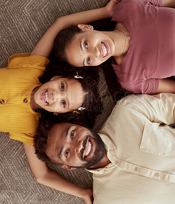 Above portrait of mixed race parents enjoying weekend with daughter in home living room. Smiling hispanic girl hugging mother and father and bonding in lounge. Happy couple lying together with child