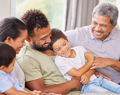 Buy stock photo Happy and content hispanic family smiling while relaxing and sitting on the couch together at home. Cheerful and carefree little brothers enjoying time with their parents and grandparents