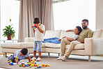 Young mixed race family bonding in the lounge while the parents relax on the couch while their two little sons play. Hispanic couple smiling while watching their boys playing in the living room