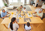 Overhead view of a mixed race family sitting at a table having lunch  in the lounge at home. Hispanic grandparents having a meal with their kids and grandkids at home
