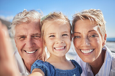 Buy stock photo Close up of little caucasian girl smiling while holding mobile phone and taking a selfie with her grandparents. Happy senior grandmother and grandfather posing for a photo with their granddaughter outdoors on a sunny day