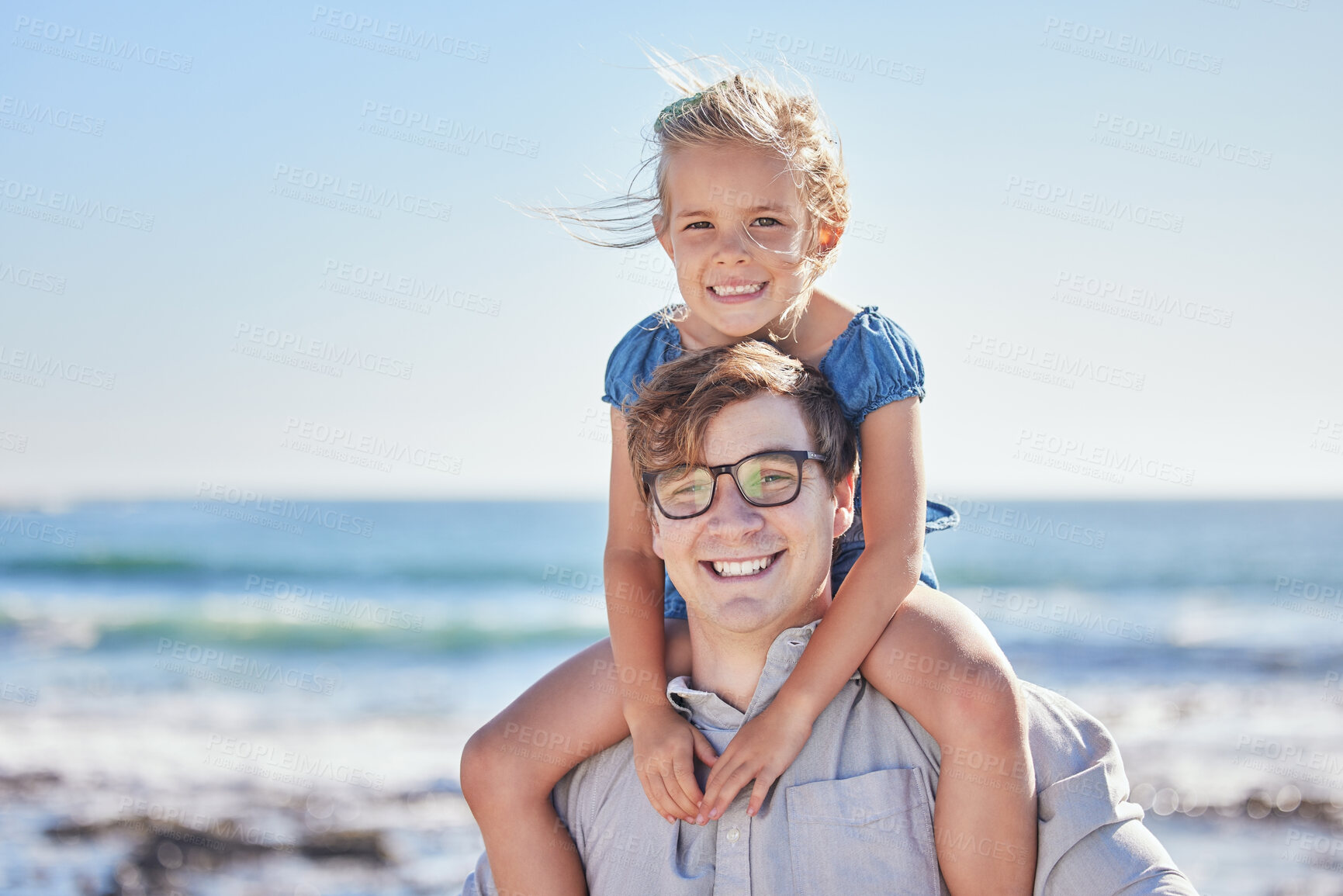 Buy stock photo Portrait of happy caucasian father with glasses carrying his daughter on his shoulders at the beach on a sunny day. Loving dad and little girl spending time together while on holiday