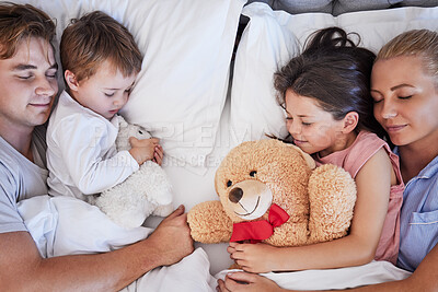 Buy stock photo Happy family with two children sleeping together in their parents bed, from above. Loving parents cuddling two little kids while holding on to their stuffed animals. Adorable girl and boy taking a nap and rest with mom and dad