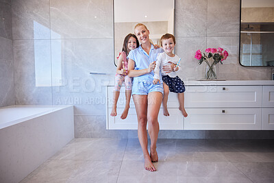Happy young caucasian family holding toothbrushes and smiling showing off their healthy teeth. Young mother and her two children getting ready in the morning and brushing their teeth