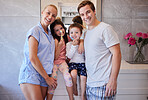Happy caucasian family with two children standing together in the bathroom while brushing their teeth with toothbrushes. Young caucasian couple teaching their children to practice good oral hygiene. Set a good example by making brushing teeth a family act