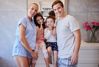 Buy stock photo Happy caucasian family with two children standing together in the bathroom while brushing their teeth with toothbrushes. Young caucasian couple teaching their children to practice good oral hygiene. Set a good example by making brushing teeth a family activity