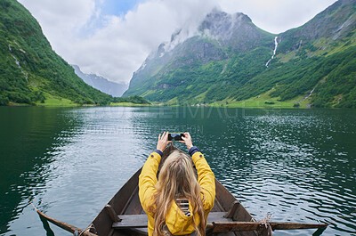 Buy stock photo Adventure woman in row boat taking photo on smart phone of beautiful fjord lake for social media