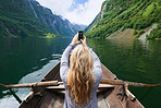 Adventure woman in row boat taking photo on smart phone of beautiful fjord lake for social media