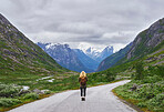 Adventure backpacking woman travels on road in epic majestic mountain snow landscape