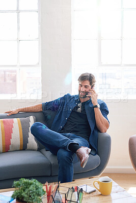 Buy stock photo Attractive man using smartphone having phone call sitting on sofa at home