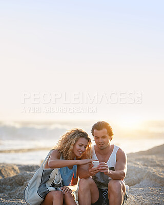 Buy stock photo Young couple using smartphone on beach at sunset
