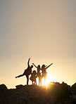 Group of friends posing standing on rocks at sunset having fun summer vacation lifestyle celebrating friendship 