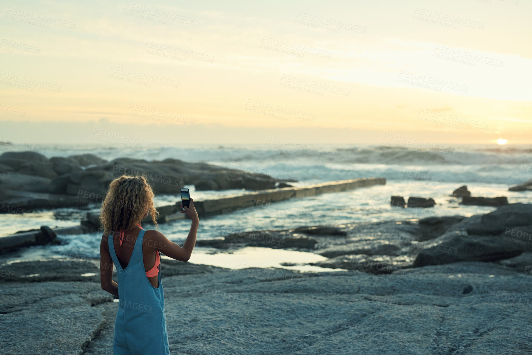 Buy stock photo woman using taking photo using smartphone on beautiful beach at sunset sharing travel lifestyle photographing seaside with mobile phone camera