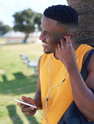 Buy stock photo African american man using smartphone listening to music relaxing outdoors in park enjoying summer