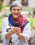 Happy senior woman using smartphone texting browsing messages on mobile phone in beautiful garden