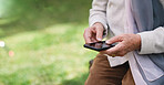 Old woman hands using smartphone texting sending messages on mobile phone outdoors