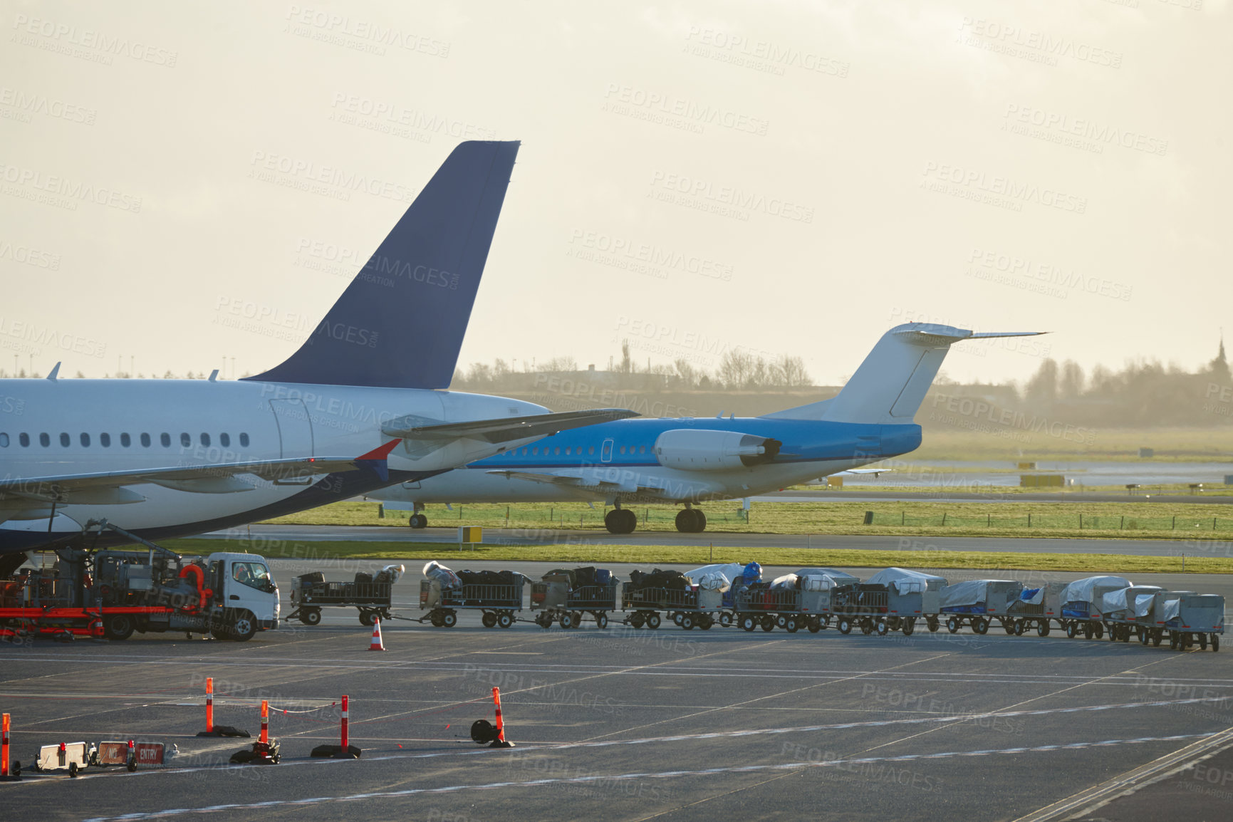 Buy stock photo View of luggage being loaded onto an airplane at an airport. Passenger plane parked at the terminal being loaded with cargo, luggage and bags with trailers