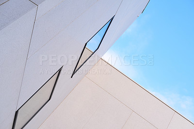 Buy stock photo Angled view of tall building exterior on a sunny day. Concept of modern white housing with reflective windows against a blue sky. Abstract background of architecture for copy space outside