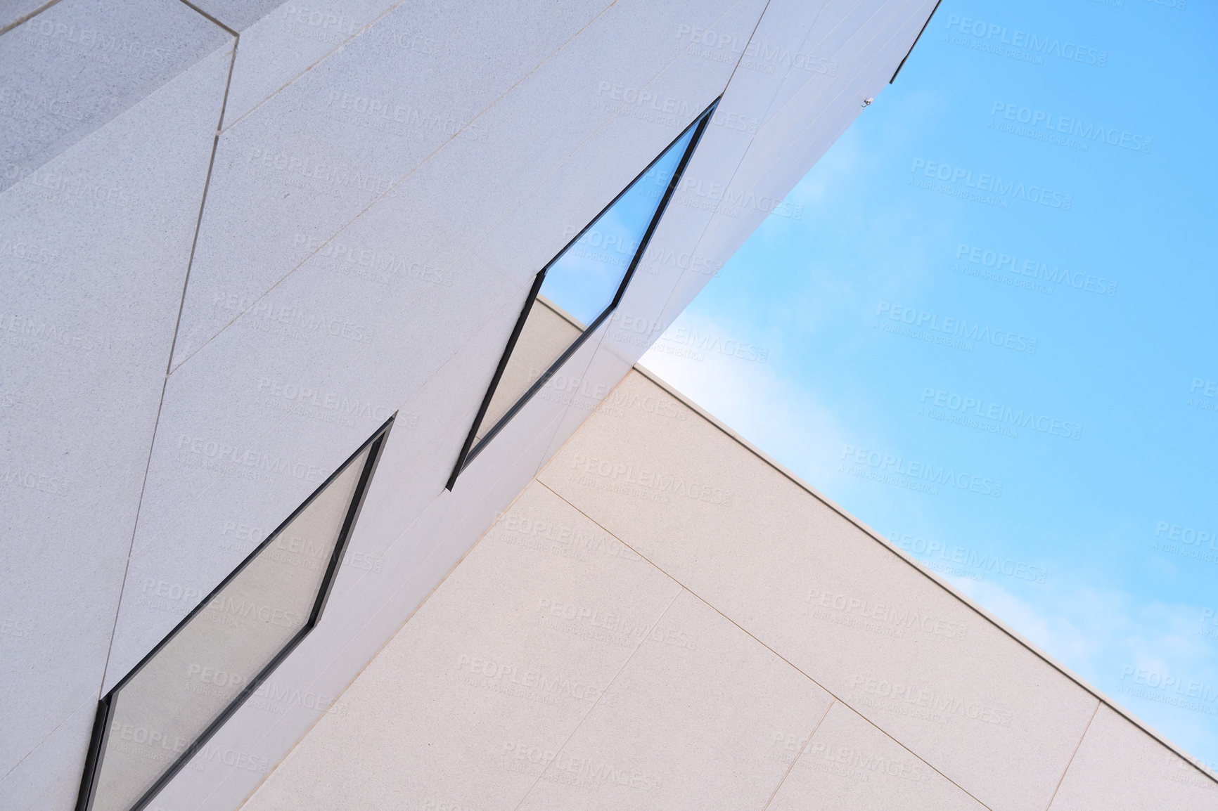 Buy stock photo Angled view of tall building exterior on a sunny day. Concept of modern white housing with reflective windows against a blue sky. Abstract background of architecture for copy space outside