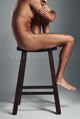 Buy stock photo Studio shot of a handsome young man sitting naked on a chair and looking sad against a grey background