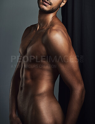 Buy stock photo Studio shot of a handsome and muscular young man posing in the nude against a grey background