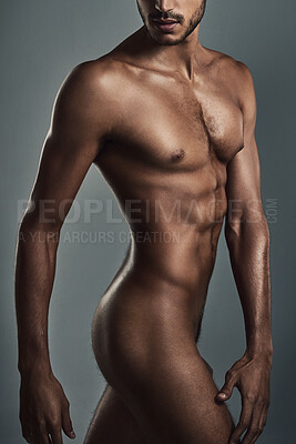 Buy stock photo Studio shot of a handsome and muscular young man posing in the nude against a grey background