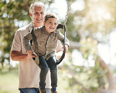 Buy stock photo Excited little caucasian boy having fun while sitting in swing and being pushed by his grandfather at the park. Active senior man bonding and playing with adorable grandson outdoors