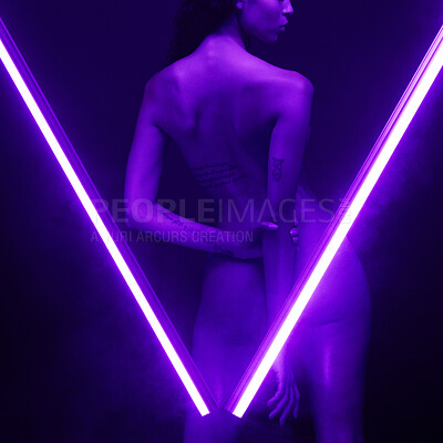 Buy stock photo Nude woman posing in studio isolated on black behind two purple neon lights. Sexy naked mixed race woman posing seductively between two beams of light in the shape of a V.