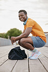 A happy sports man taking break from exercising. An African American man looking at the camera while resting on planks. A confident young sporty guy resting.