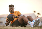 A sporty man exercising, working on his fitness. An african american male athlete using a medicine ball, living an active, healthy lifestyle, sitting on the grass doing sit ups