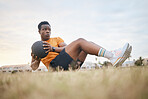 A sporty man exercising, working on his fitness. An african american male athlete using a medicine ball, living an active, healthy lifestyle, sitting on the grass doing sit ups